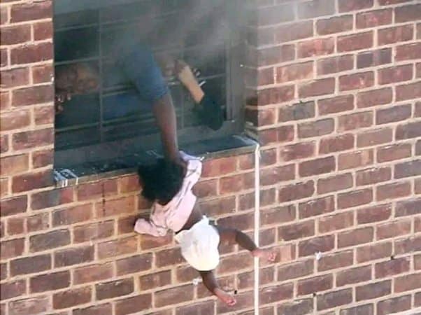 Vanessa Scott dangles her relative Kid out of the window of a burning apartment 